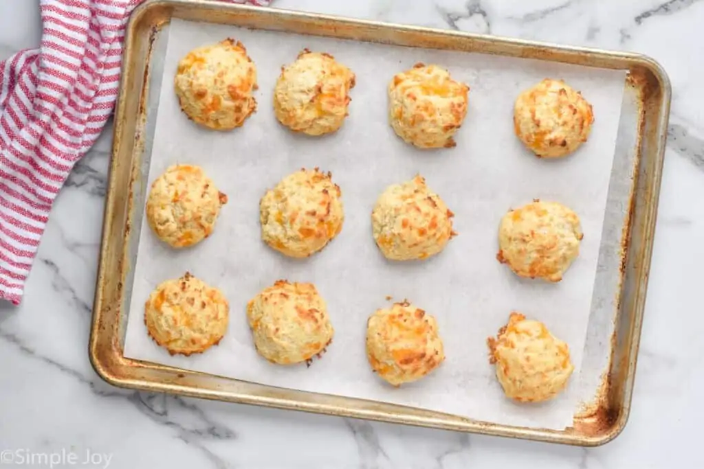 overhead photo of biscuits on a rimmed baking sheet with parchment paper