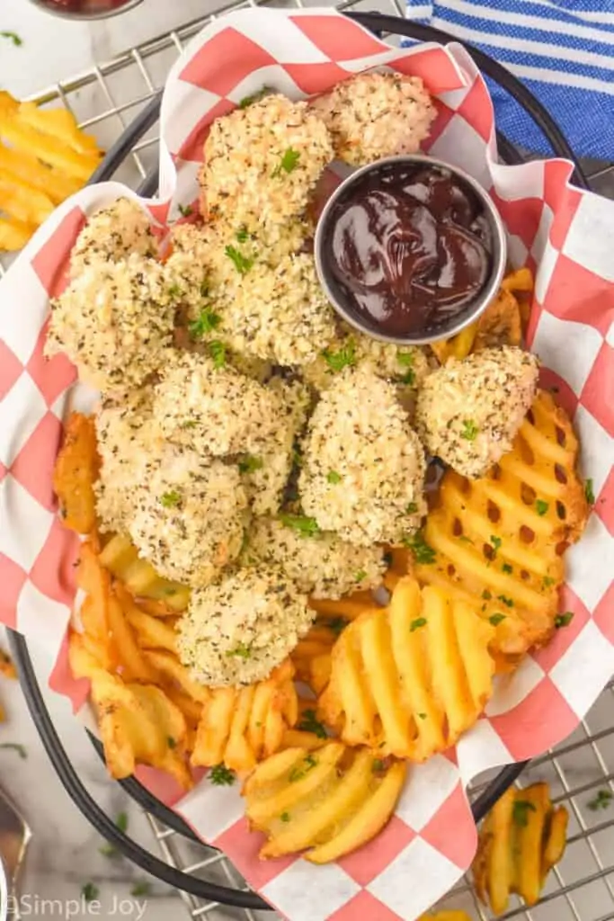 overhead of a basket full of parmesan crusted chicken nuggets and waffle fries