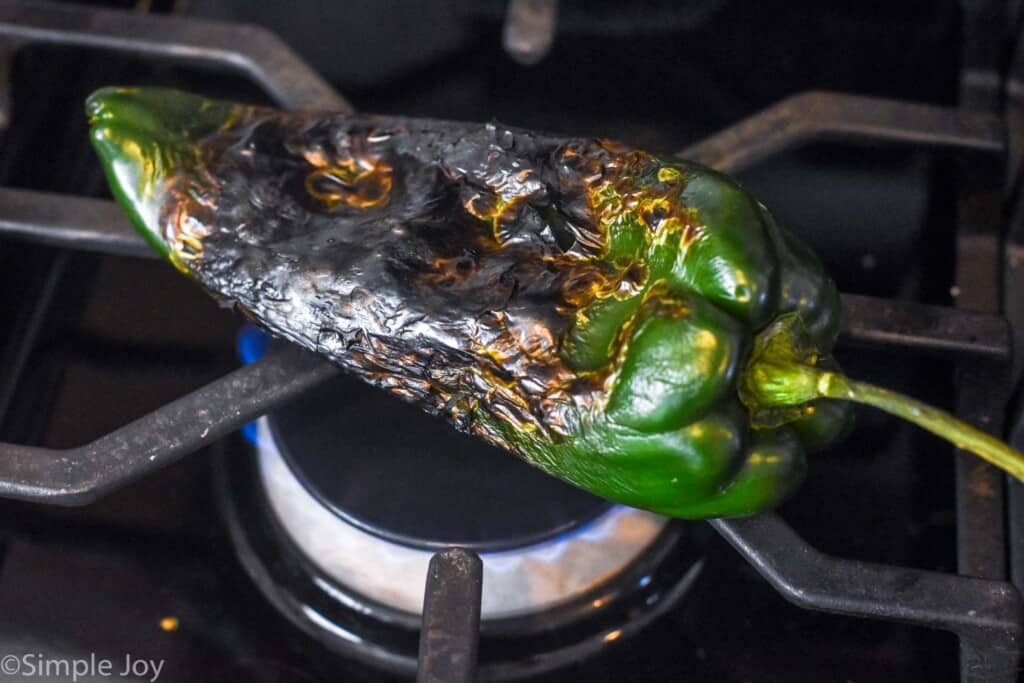 poblano pepper being roasted on a burner