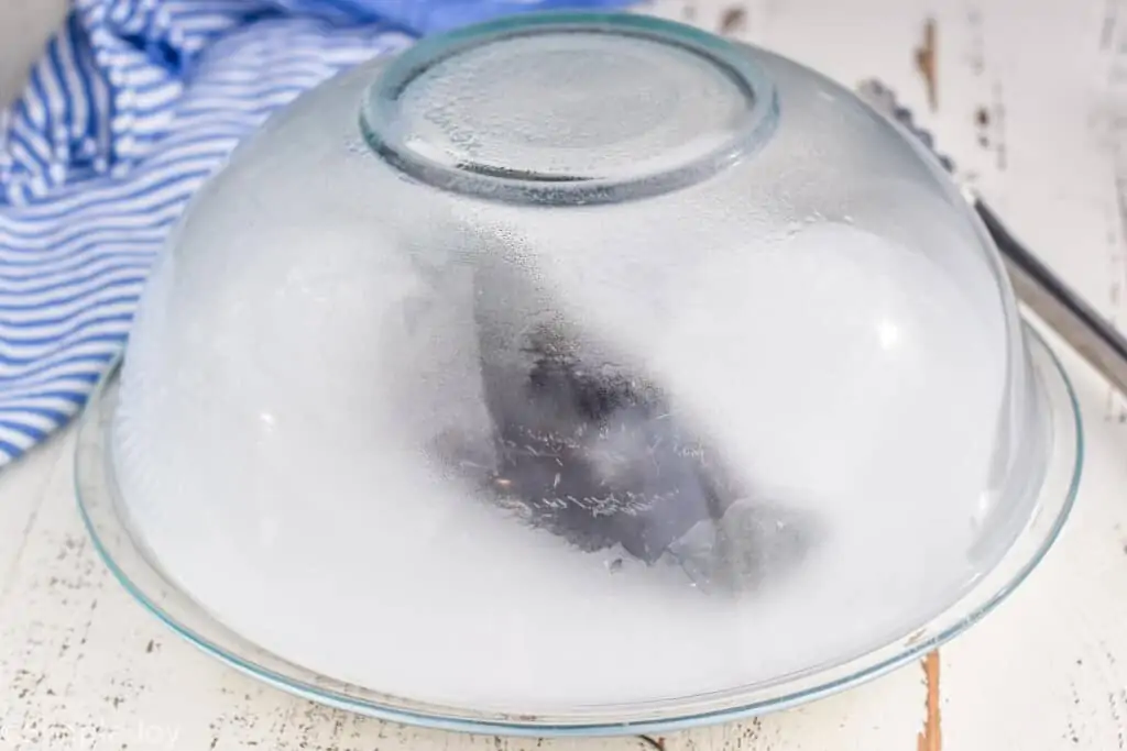 poblano pepper being steamed under a glass bowl