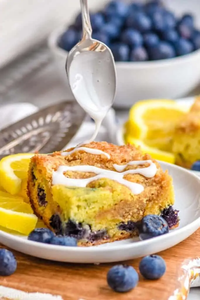 icing being drizzled over a piece of coffee cake on a plate