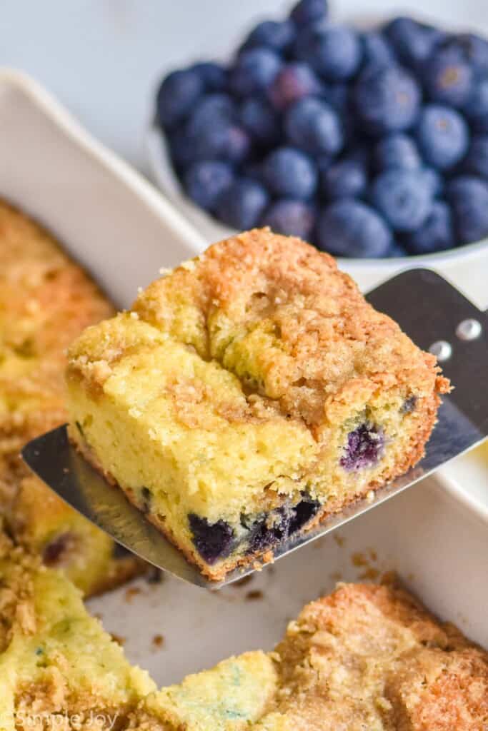 a piece of blueberry coffee cake being served out of a dish