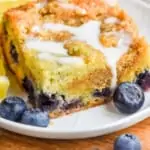 pinterest graphic of a piece of blueberry coffee cake on a plate with a drizzle of icing on top