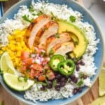 overhead of a burrito bowl with chicken, rice, avocado, beans, salsa, and corn