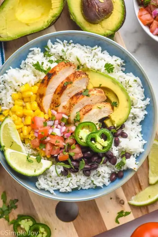 overhead of a burrito bowl with chicken, rice, avocado, beans, salsa, and corn