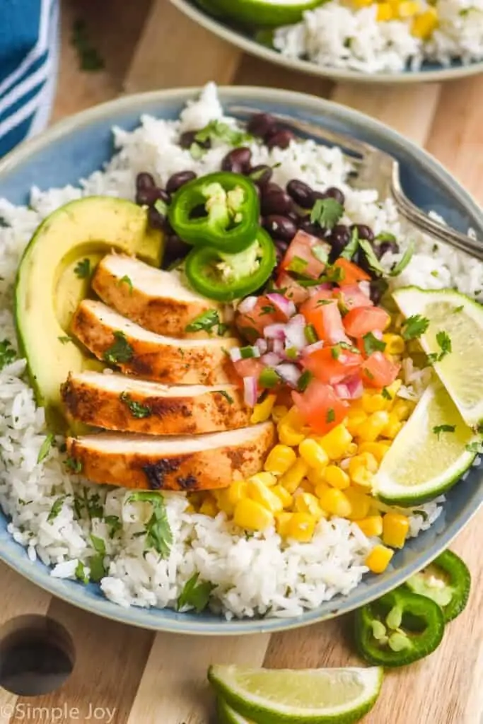 a burrito bowl recipe with chicken, cilantro lime rice, corn, avocado, Pico de Gallo, beans, and fresh jalapeños