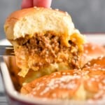 a cheeseburger slider being pulled out of a pan