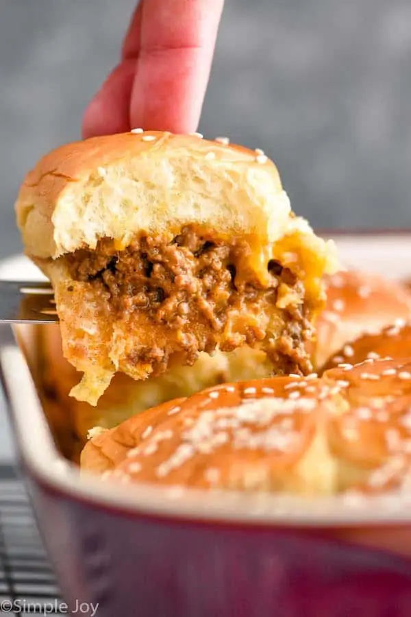 a cheeseburger slider being pulled out of a pan