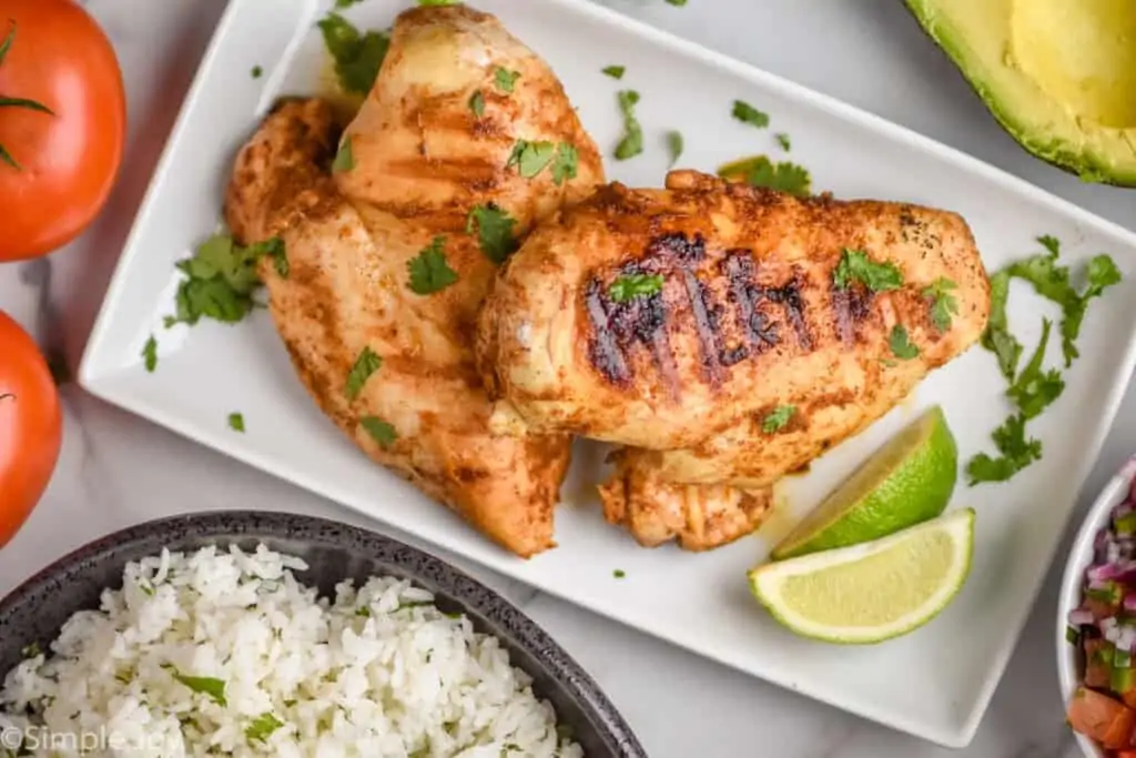 overhead of two chicken breasts on a plate that have been grilled and garnished with cilantro