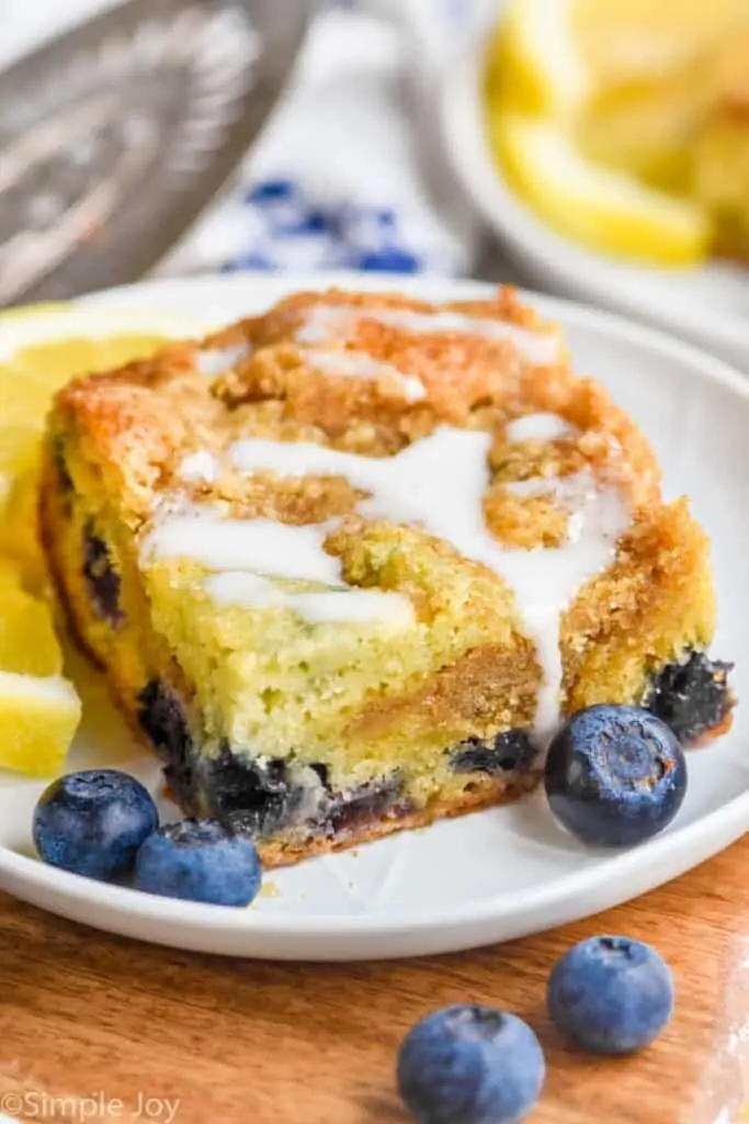 a piece of blueberry coffee cake on a plate with a drizzle of icing on top