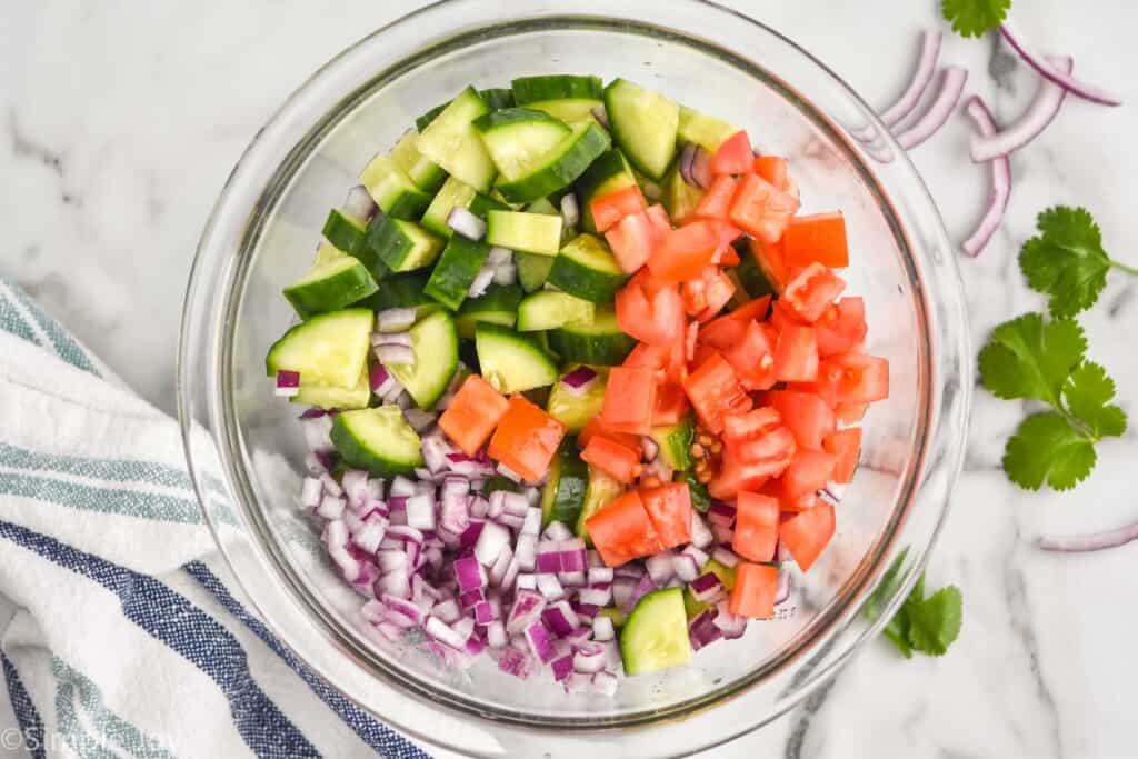 overhead of ingredients to make a salad with cucumber and avocado