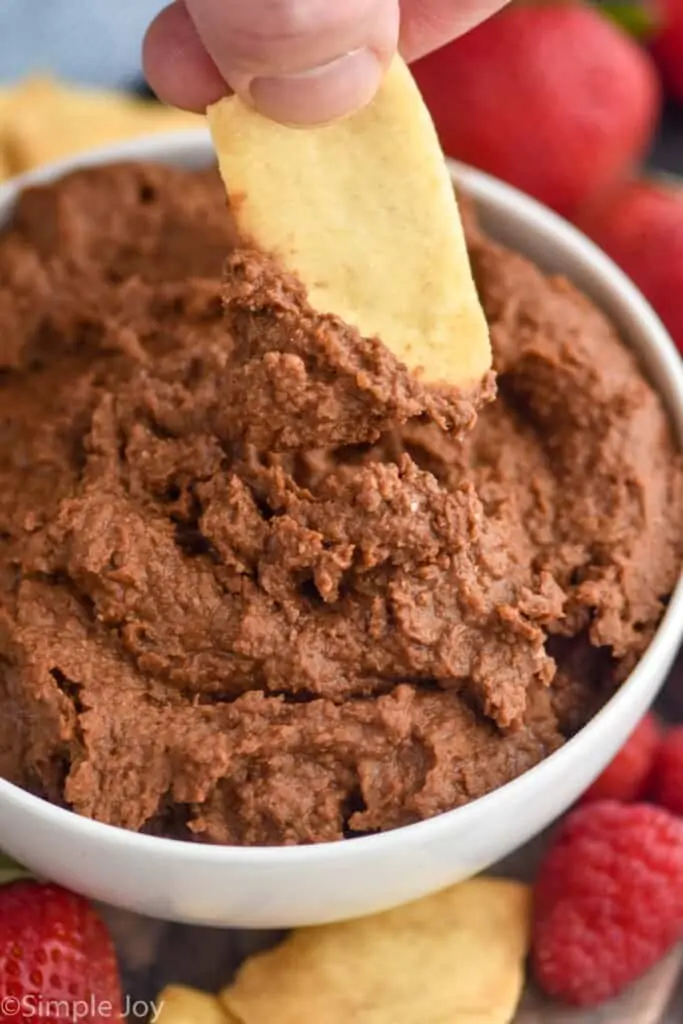 close up of a pita chip dipping in dark chocolate hummus