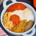 a small, shallow, blue dish with handles on a black surface, filled with hamburger seasoning broken up by seasoning - 13