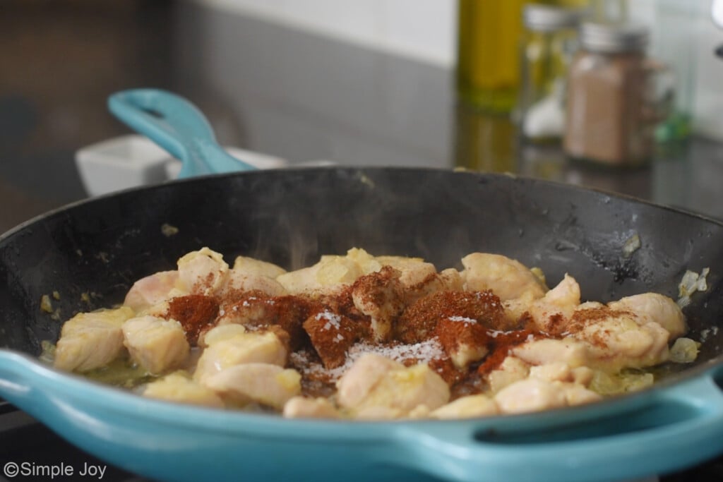 a frying pan of chicken with seasonings to make butter chicken