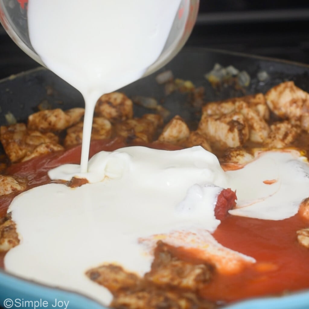 adding half and half to a skillet to make butter chicken