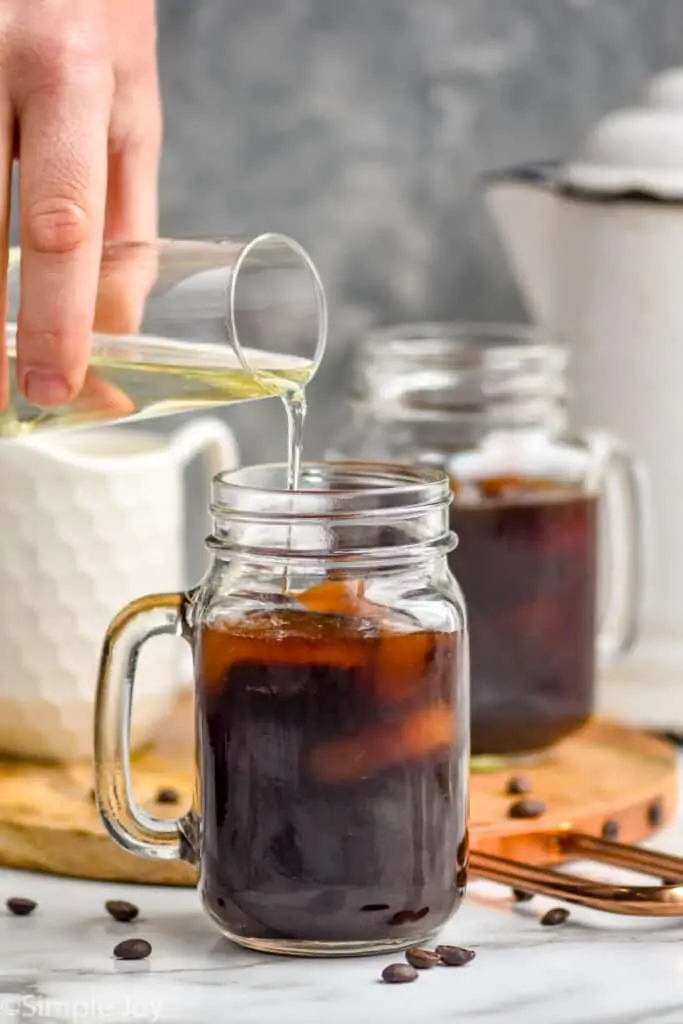 simple syrup being poured into iced coffee