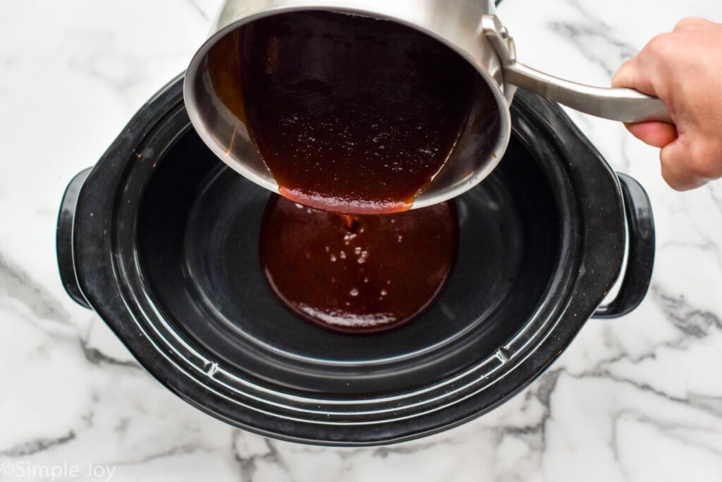 pouring a little bbq sauce into the bottom of a slow cooker