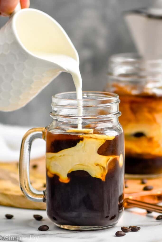 half and half being poured into an iced coffee