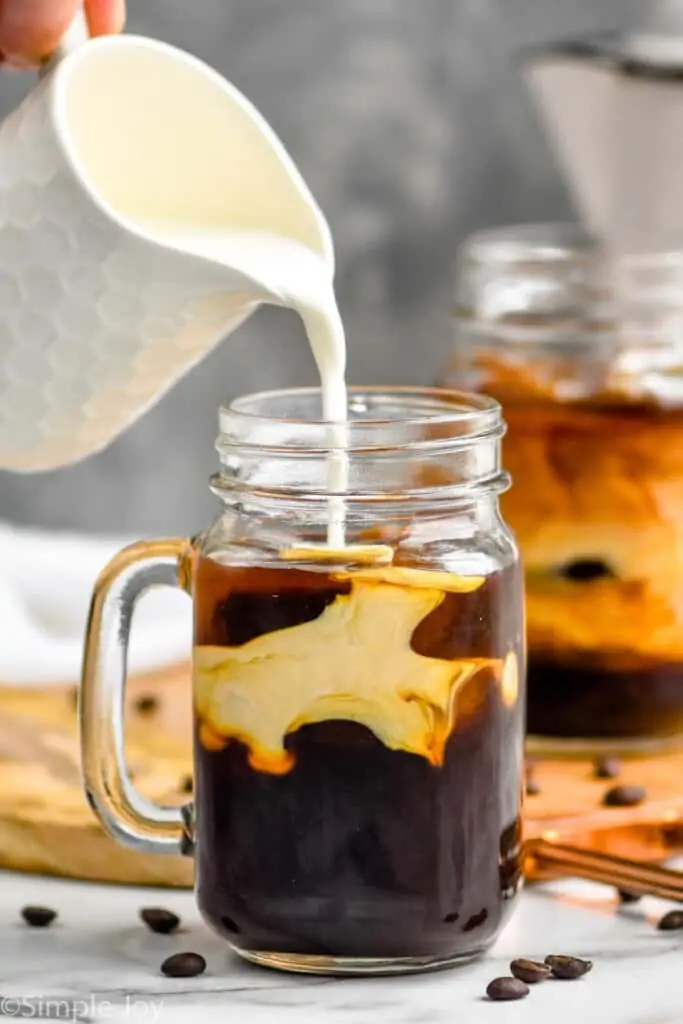 half and half being poured into an iced coffee