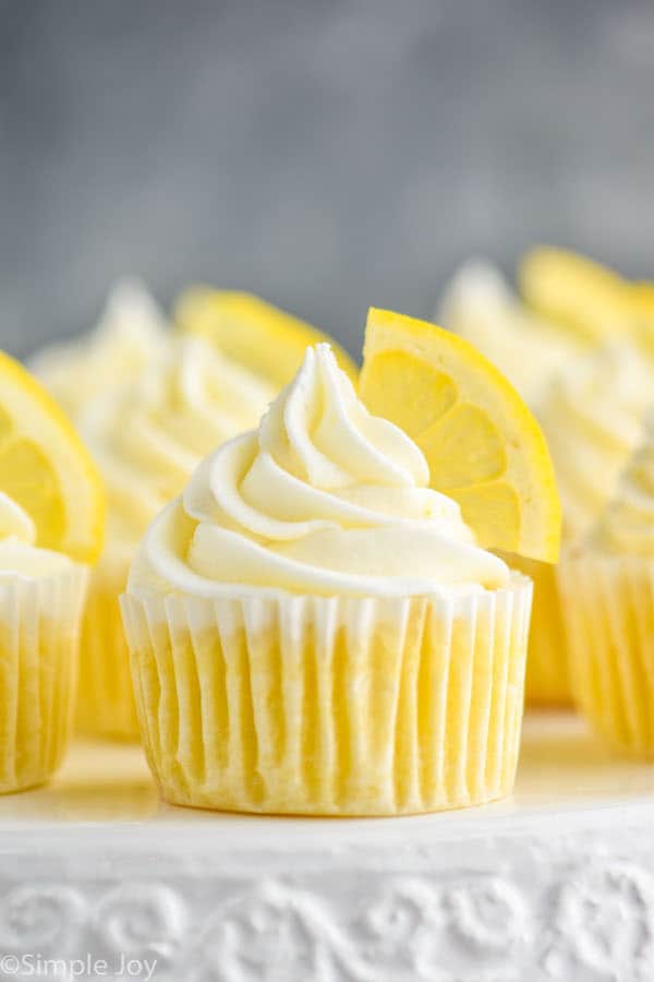 up close picture of lemon cupcakes topped with frosting swirl and a lemon wedge