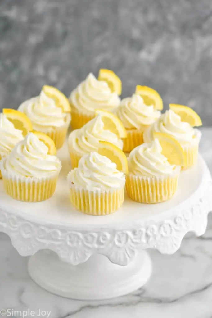 a bunch of lemon flavored cupcakes on a white cake stand