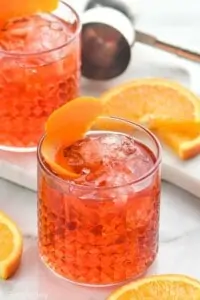 tumbler with Negroni recipe garnished with an orange peel