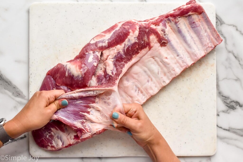 a woman removing the membrane from the back of ribs