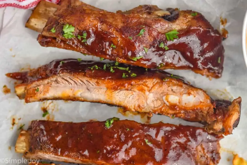 close up of slow cooker spare ribs after cooking, slathered in bbq sauce