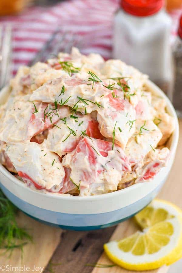 side view of a bowl of crab salad garnished with fresh dill