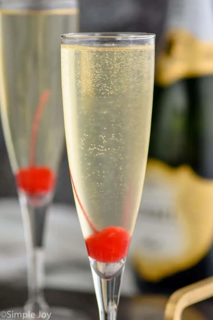 close up of a champagne flute garnished with a cherry at the bottom holding a French 76 recipe