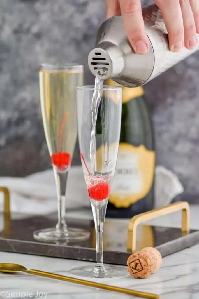 alcohol being poured into a champagne flute from a shaker