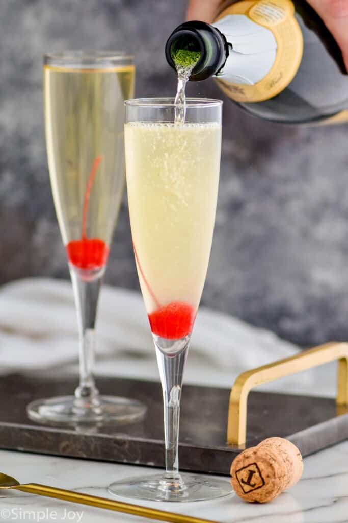 champagne being poured into a flute to top off a French 76 recipe