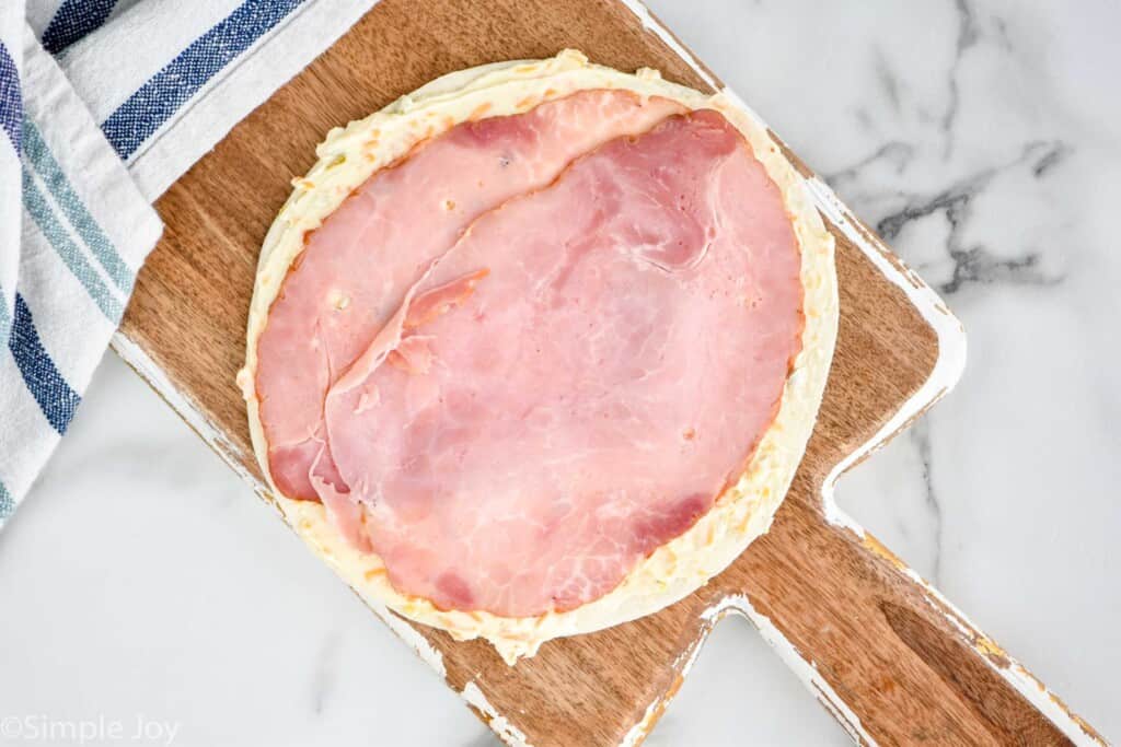 a tortilla with cream cheese mixture and ham slices