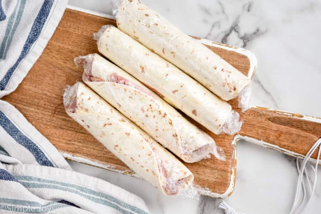 four ham and cream cheese roll ups, wrapped in Saran Wrap