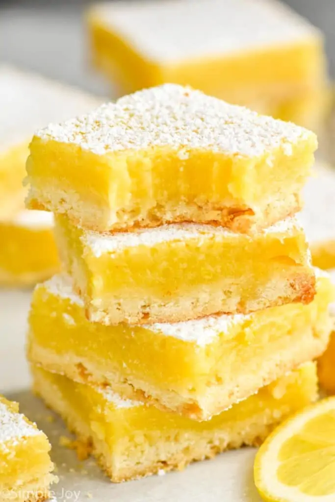 four lemon bars stacked with a bite missing out of the top one