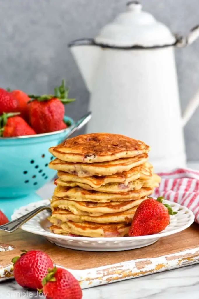 stack of strawberry pancakes on a white plate
