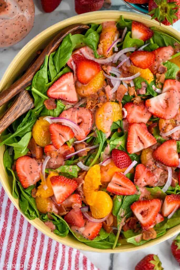 overhead of a strawberry salad with sliced strawberries, mandarin oranges, bacon, and red onions