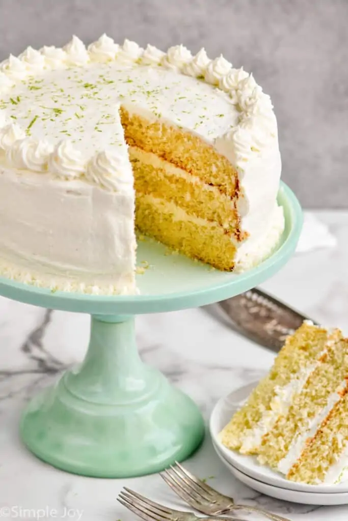 a whole key lime cake recipe on a cake stand with a piece missing