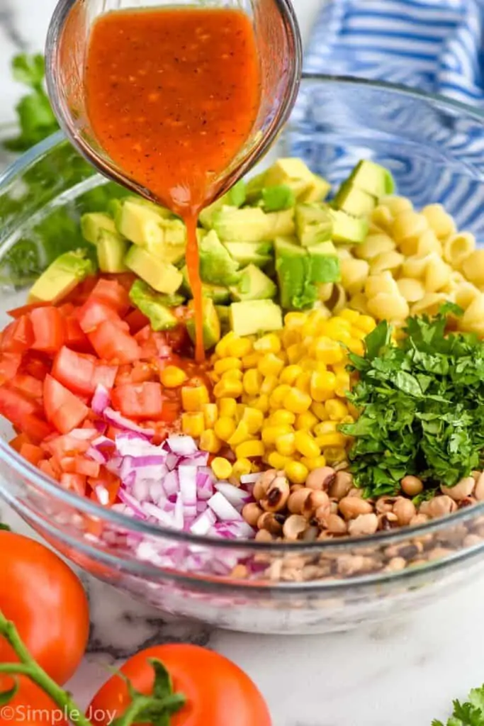 dressing being poured over cowboy caviar pasta salad