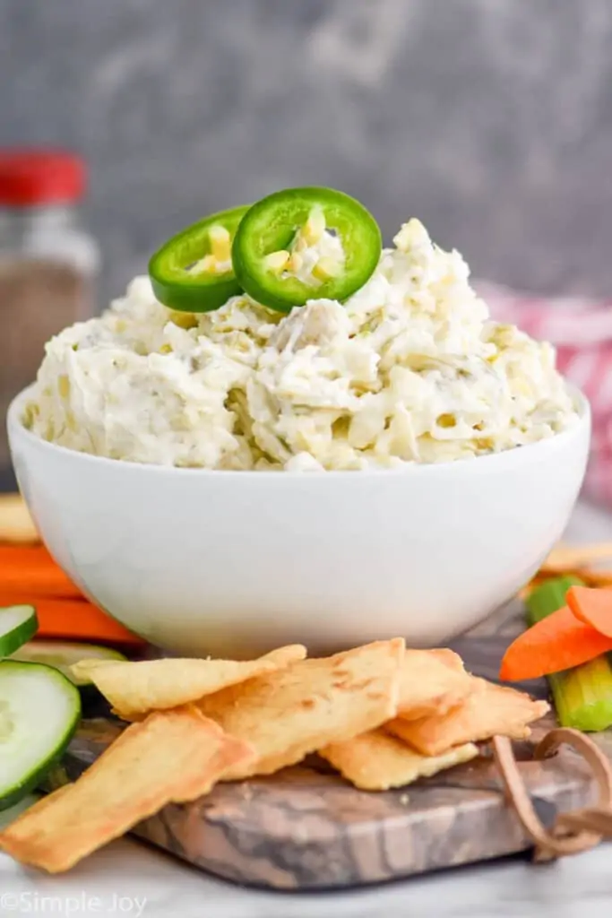 side view of a cold cream based dip in a small white bowl garnished with jalapeno slices