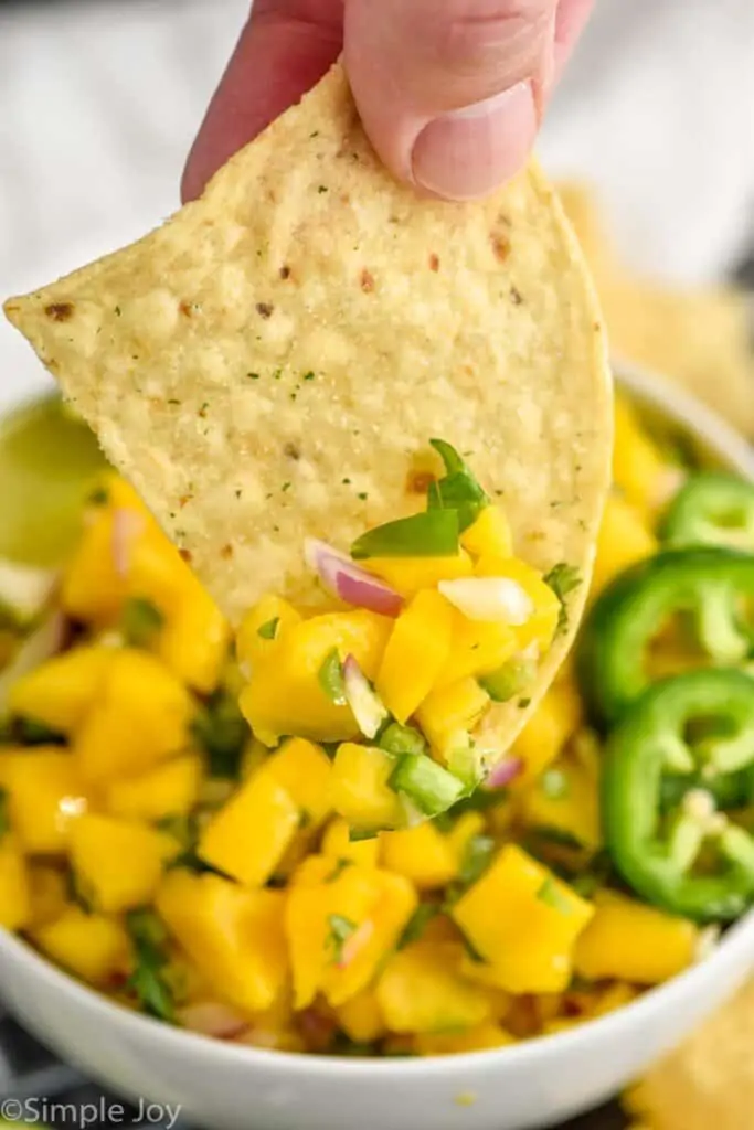 a chip scooping up mango Pico de Gallo