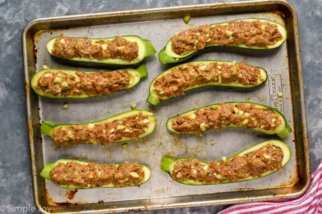overhead of stuffed zucchini boats, uncooked on a rimmed baking sheet