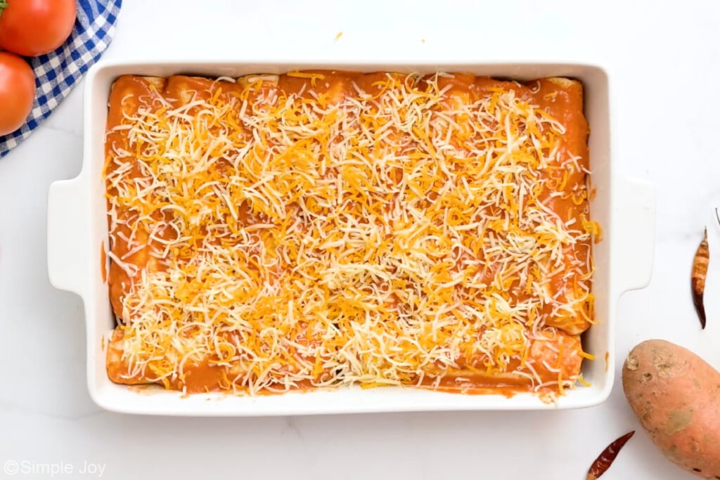 overhead of baking dish of black bean enchiladas topped with shredded cheese - 10