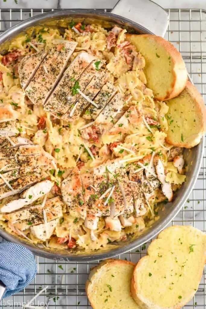 overhead of sun dried tomato pasta with chicken cut up on top of the pasta