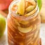 apple pie filling being spooned out of a large mason jar