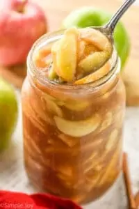 apple pie filling being spooned out of a large mason jar