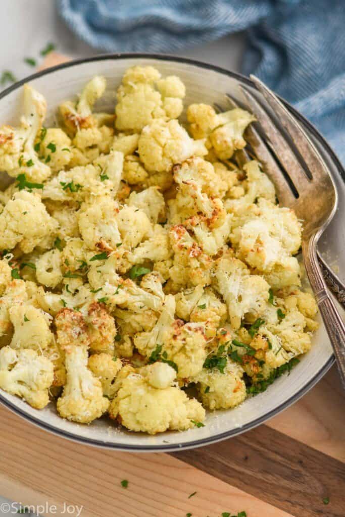 cauliflower that has been cooked in an air fryer in a serving bowl garnished with cheese and parsley