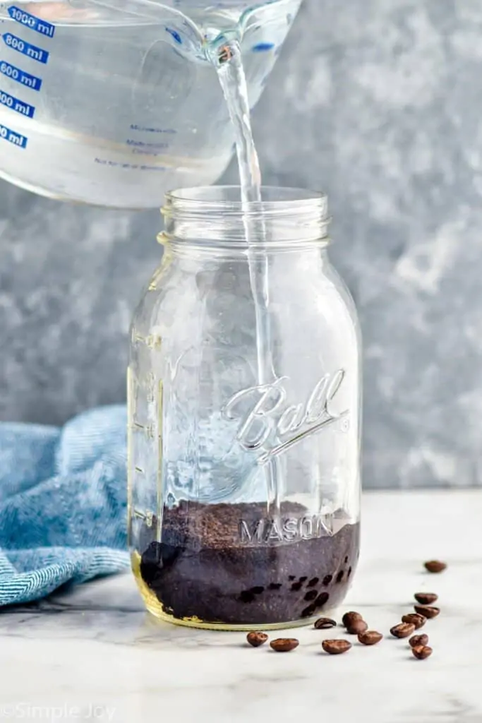 pouring water into a mason jar that has coffee grounds in it