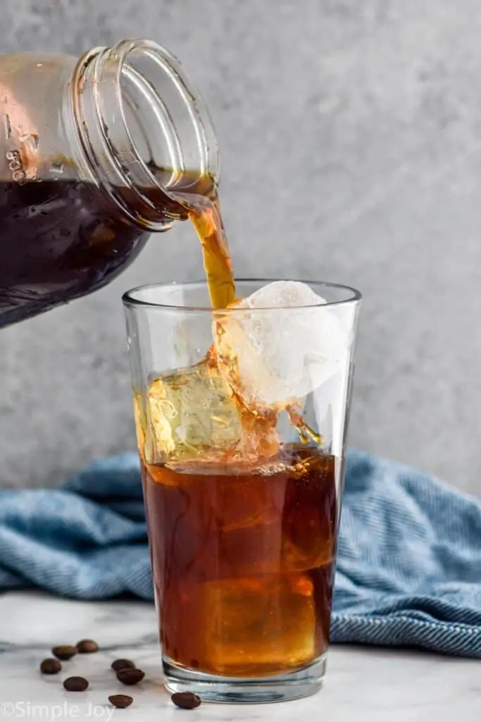 pouring a cold brew recipe over a ice in a glass tumbler