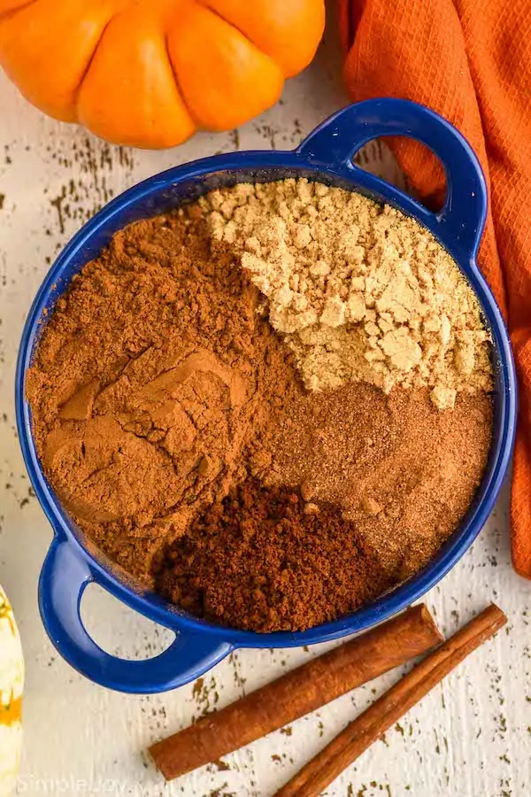 pinterest graphic of overhead of a small blue dish with the four different spices that make up pumpkin pie spice